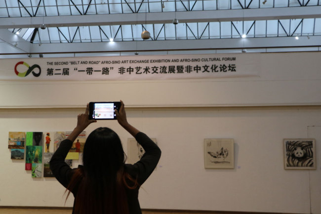 A visitor takes a picture of the art works displayed at the Second Belt and Road Afro-Sino Art Exhibition. The exhibition is launched the National Gallery of Zimbabwe on Monday, April 29, 2019. [Photo: China Plus/Gao Junya]