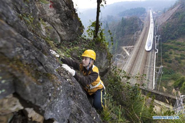Zhang Yi, a bridge and tunnel worker born in the 1990s, is seen at an observation point while a bullet train runs on the railway in Yichang, central China's Hubei province, Jan. 19, 2017. [File photo: Xinhua]