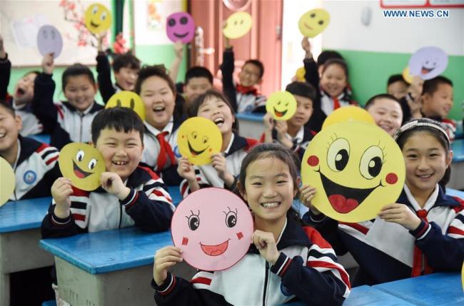 Pupils demonstrate smiley cards(卡片 kǎpiàn) to greet the upcoming World Smile Day at a primary school in Handan, north China's Hebei Province, May 7, 2019. [Photo: Xinhua]