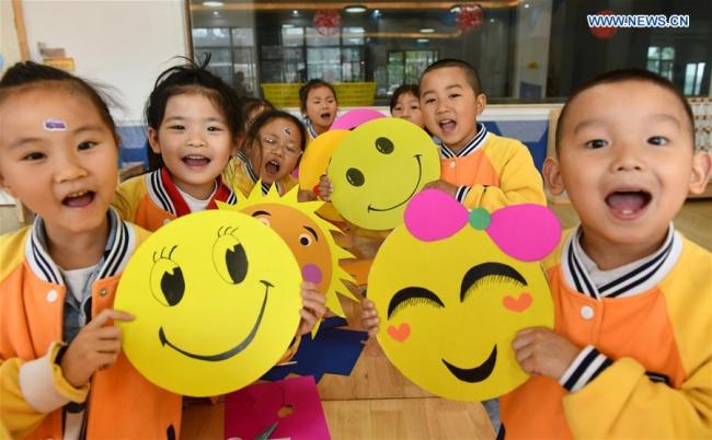 Kids demonstrate smiley cards(卡片 kǎpiàn) to greet the upcoming World Smile Day at a kindergarten in Zigui County, central China's Hubei Province, May 7, 2019. [Photo: Xinhua]