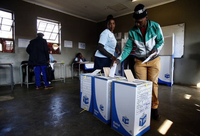 An Independent Electoral Commission (IEC) official assists a man to cast his vote at Rakgatla secondary school polling station during South Africa's national and provincial elections on May 8, 2019 in Marikana. [Photo: AFP]