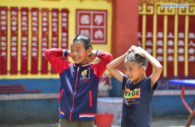 Two boys wash their hair at Nongyong Primary School in Bansheng Township of Dahua Yao Autonomous County, south China's Guangxi Zhuang Autonomous Region, May 10, 2019. [Photo: Xinhua/Huang Xiaobang]