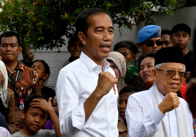 Indonesian President Joko Widodo (C) and his running mate Ma'ruf Amin (R) gesture while visiting a neighbourhood in Jakarta on May 21, 2019. [Photo: AFP]