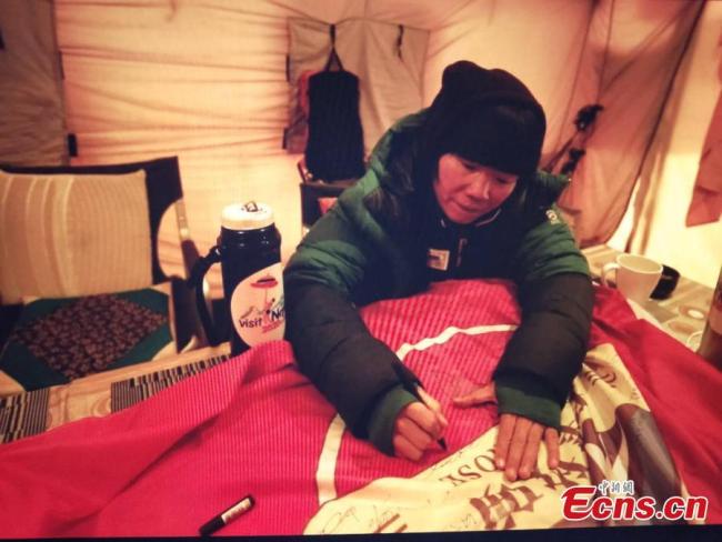 A female mountaineer signs a banner before climbing Mount Qomolangma, known as Mount Everest in the West, on May 22, 2019. [Photo: China News Service]<br/><br/>