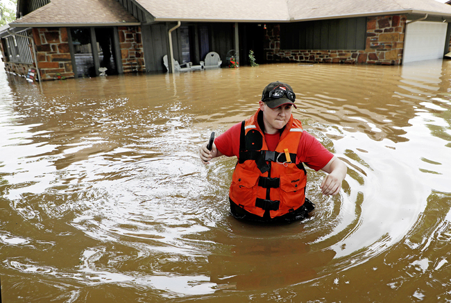 Tulsa County Sheriff's Deputy Miranda Munson makes her way back to a fan boat after checking a flooded house for occupants in the Town and Country neighborhood in Sand Springs, Oklahoma, Thursday, May 23, 2019. [Photo: AP]