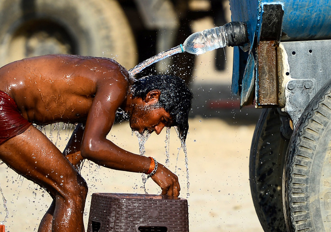 An Indian truck driver takes a bath using a water tanker as he tries to cool himself on a hot summer afternoon in Allahabad on May 31, 2019. [Photo: AFP]