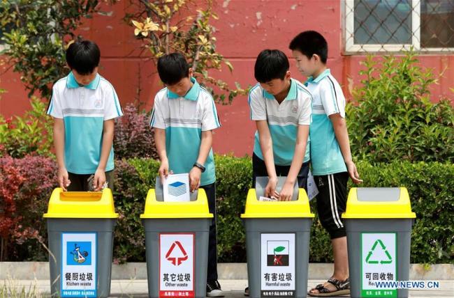 Students throw wastes into rubbish bins(垃圾箱 lājī xiāng) according to garbage sorting in Xingtai, north China's Hebei Province, June 4, 2019. [Photo: Xinhua]