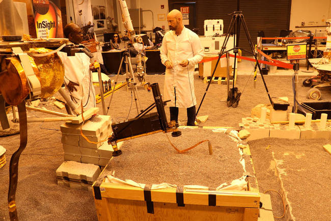 Engineers in a Mars-like test area at NASA's Jet Propulsion Laboratory try possible strategies to aid the Heat Flow and Physical Properties Package (HP3) on NASA's InSight lander, using engineering models of the lander, robotic arm and instrument. [Photo: nasa.gov]