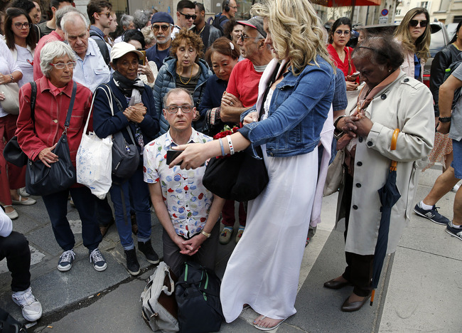 Worshippers pray as they watch the first mass inside Notre Dame cathedral displayed on a mobile phone next to the cathedral on June 15, 2019, in Paris, France. [Photo: VCG]