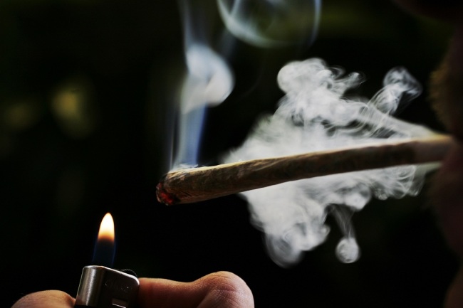 A regular user of soft drugs lights a marijuana joint in a coffee shop. [File Photo: IC] 