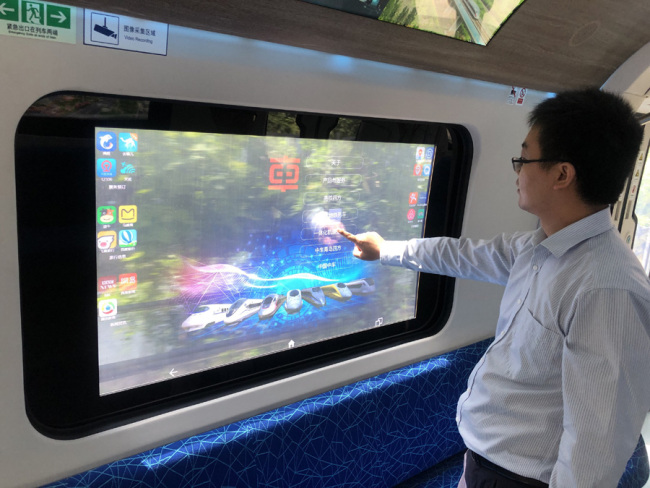 A staff member displays how to use the touch screen on the window of the carriage. [Photo: IC]