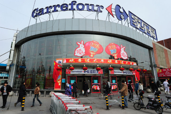 In this file photo taken on January 27, 2011 a man carrying his bags of groceries steps out of a Carrefour store in Beijing. [Photo: AFP/ Frederic J. BROWN]