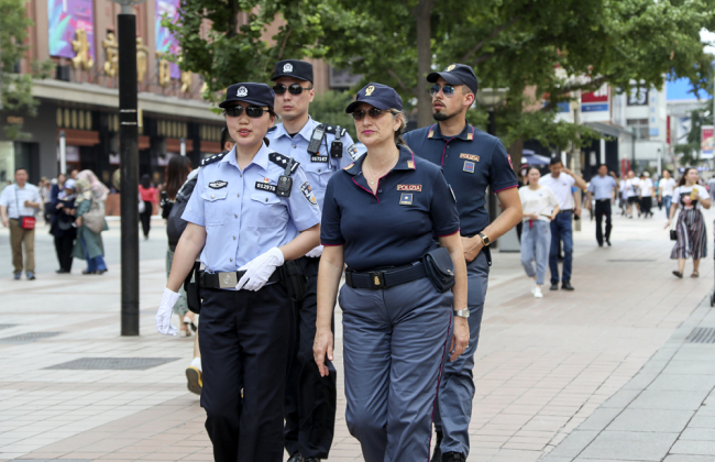 Italian and Chinese police officers walk through the crowd as they carry out a joint patrol on Wangfujing Street in downtown Beijing on June 24, 2019. [Photo: VCG]