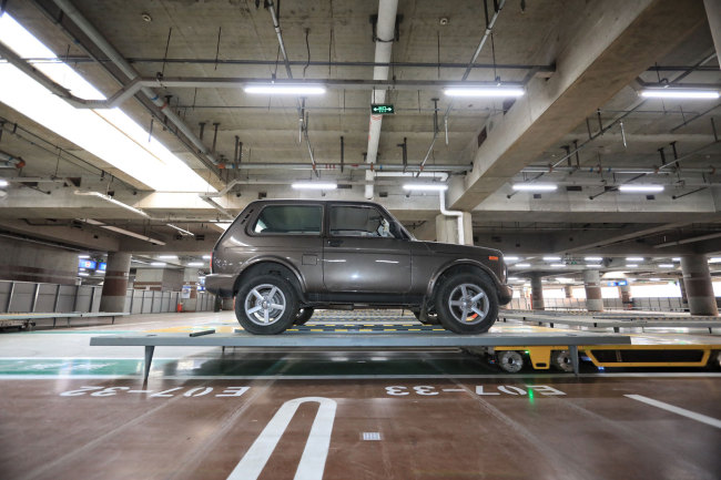 A robot carrying a car to a parking spot runs through the intelligent parking lot at the Beijing Capital International Airport on Tuesday, June 25, 2019. [Photo: IC]