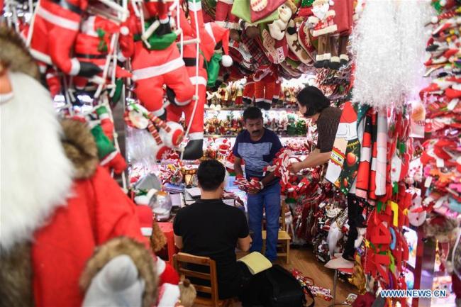 A foreign businessman(C) selects(挑选 tiāoxuǎn) Christmas commodities at the Yiwu International Trade City in Yiwu, east China's Zhejiang Province, June 26, 2019. [Photo: Xinhua]