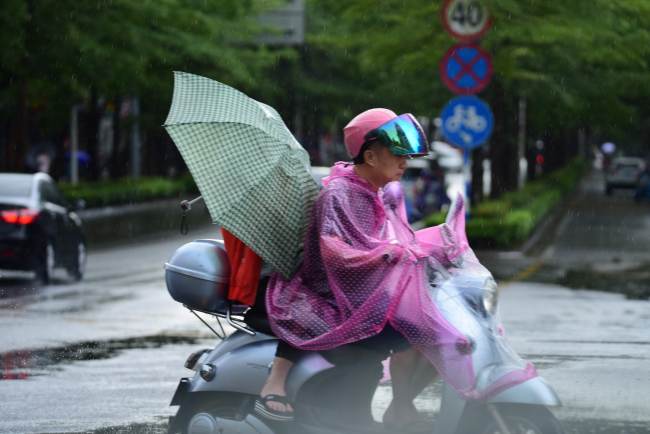People riding bikes in the rain caused by the tyhoon Mun on July 3, 2019. [Photo: IC]