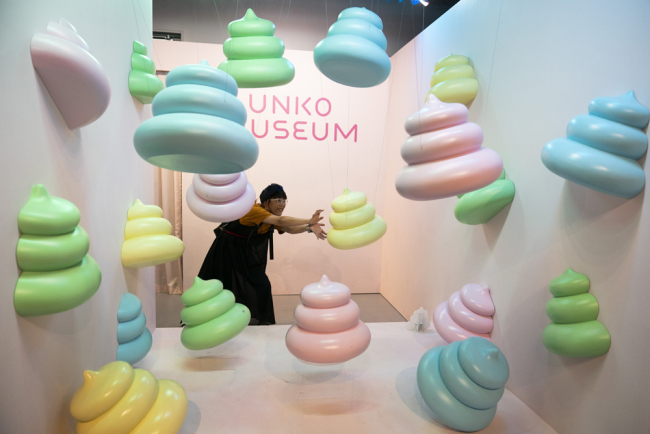 A woman jokingly poses with large poop-shaped figurines at the Unko Museum in Yokohama, south of Tokyo, July 18, 2019. [Photo:IC]
