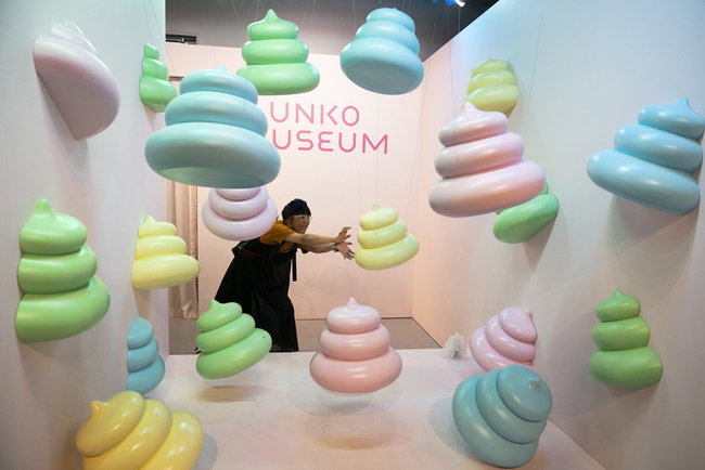 A woman jokingly poses with large poop-shaped figurines at the Unko Museum in Yokohama, south of Tokyo, July 18, 2019. [Photo:IC]