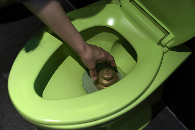 A visitor reaches into a toilet bowl to pick up toy poop at the Unko Museum in Yokohama, south of Tokyo, July 18, 2019. [Photo:IC]