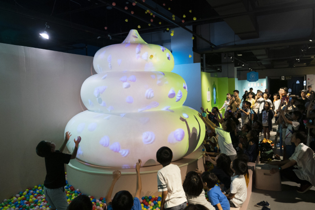 A group of children try to catch small poop toys gushing from a giant poop-shaped inflatable at the Unko Museum in Yokohama, south of Tokyo, July 1, 2019. [Photo:IC]