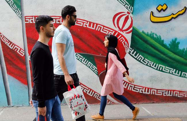 Iranians walk past a graffiti on a wall of the national flag, on the eve of the first anniversary of the US withdrawal from the Iran nuclear deal, in Tehran, Iran, May 7, 2019. [File Photo: IC]