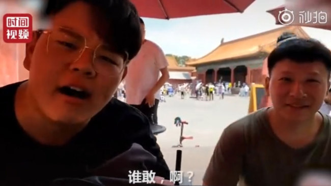 Two male tourists sit in a public rest area and smoke inside the Palace Museum in Beijing on Sunday, July 7, 2019. [Photo: Screenshot]