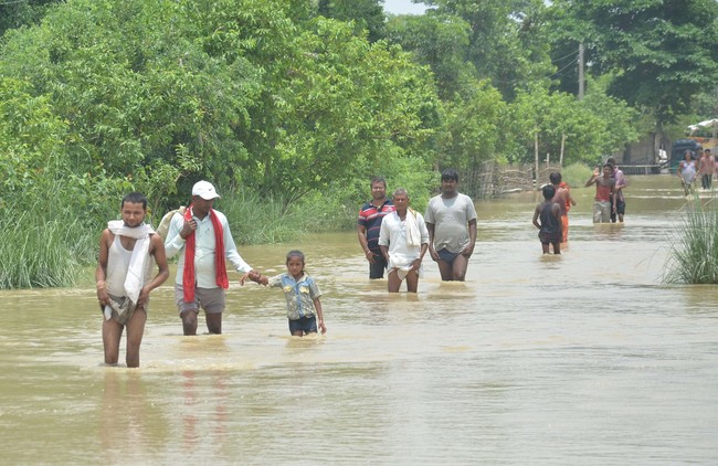 People cross a flooded street following incessant monsoon rainfall, at Aurai Block, on July 16, 2019, in Muzaffarpur, India. [Photo: VCG/Getty Editorial/Hindustan Times]