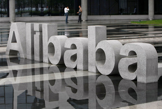 Two men chat beside a logo of Alibaba Technology Co. Ltd at its headquarters on the outskirts of Hangzhou, Zhejiang Province on May 17, 2010. [File photo: VCG/Steven Shi]