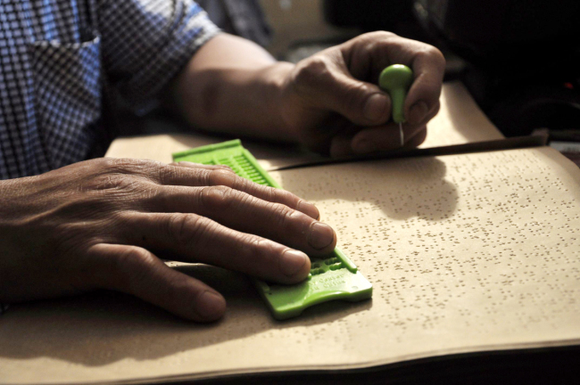 A man writes braille. [File photo: VCG]