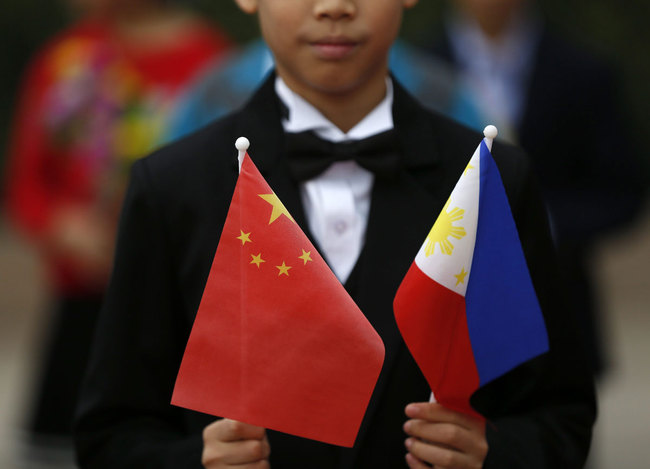 A Chinese boy holds the Chinese and Philippines national flags. [File photo: IC]