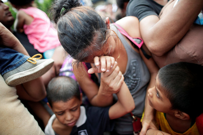 A Honduran migrant, part of a caravan trying to reach the U.S., reacts with her children after storming a border checkpoint to cross into Mexico, in Tecun Uman, Guatemala October 19, 2018. [Photo: VCG]<br><br>