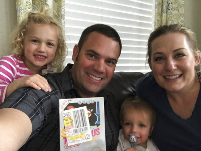 In this June 15, 2019 photo provided by Heritage Auctions, Scott Amos, along with his wife, Kristy, and daughters Grace, left, and Katie, pose in Reno, Nev., with an unopened copy of a 1987 cult-classic video game "Kid Icarus."  [File photo: AP]