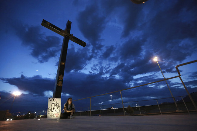 A woman sits next to a sign with a message that reads: ¨No More Guns! Make Love¨, in Juarez, Mexico, Saturday, Aug. 3, 2019, where people are gathering for a vigil for the 3 Mexican nationals who were killed in an El Paso shopping-complex shooting. Twenty people were killed and more than two dozen injured in a shooting Saturday in a busy shopping area in the Texas border town of El Paso, the state’s governor said. [Photo: AP]