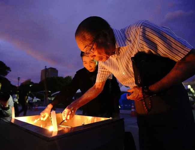 Residents light candles to mourn victims in the early morning prior to the memorial service for atomic bomb victims at the Peace Memorial Park in Hiroshima on August 6, 2019. [Photo: JIJI PRESS/AFP via VCG]