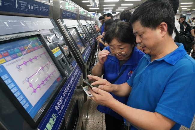 Passengers learn to buy subway tickets using a new cashless payment method at a subway station in Beijing on August 10, 2019. [Photo: VCG]