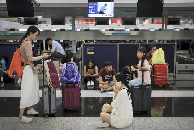 Travelers gather at the closed check-in counters as protesters stage a protest at the Hong Kong International Airport, Monday, Aug. 12, 2019. [Photo: AP/Kin Cheung]