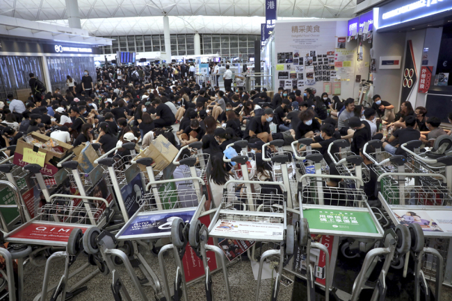 Protesters use luggage trolleys to block the walkway to the departure gates during a demonstration at the Airport in Hong Kong, Tuesday, Aug. 13, 2019. [Photo: AP/Vincent Yu]