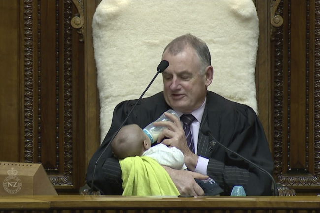 In this Wednesday, Aug. 21, 2019, image from video, New Zealand House Speaker Trevor Mallard bottle-feeds lawmaker Tamati Coffey's baby, Tutanekai Smith-Coffey, while presiding over a debate in parliament in Wellington, New Zealand. [Photo: Parliament TV via AP]