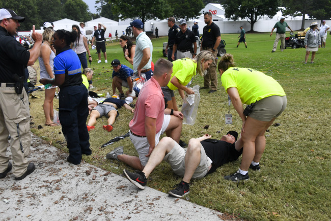 Spectators are tended to after a lightning strike on the course left several injured during a weather delay in the third round of the Tour Championship golf tournament Saturday, Aug. 24, 2019, in Atlanta. [Photo: AP/John Amis]