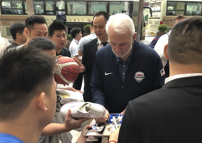 U.S. men's basketball coach Gregg Popovich signs autographs for fans Thursday, Aug. 29, 2019, at the team hotel in Shanghai upon arrival for the World Cup. The team will play three first-round games starting Sunday. [Photo: AP/Tim Reynolds]