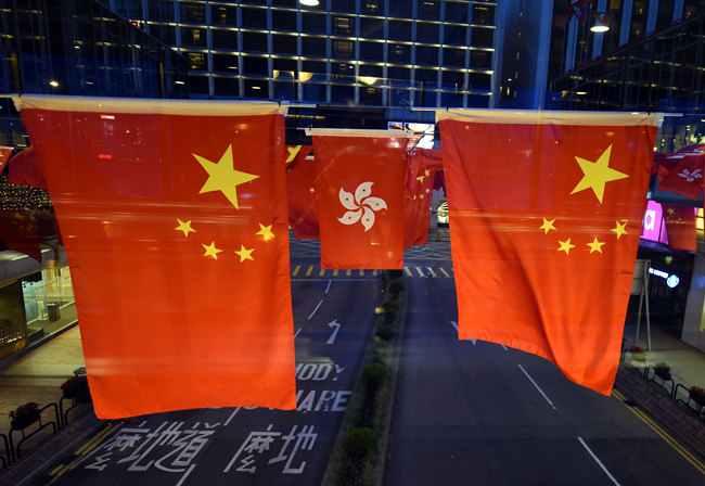 Vehicles drive under flags of China and Hong Kong Special Administrative Region of the People's Republic of China decorated to mark the 20th anniversary of Hong Kong's return to the motherland, in Hong Kong, on June 25, 2017. [File Photo: IC]