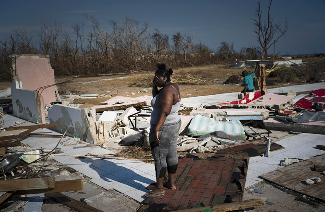 A woman is overcome as she looks at her house destroyed by Hurricane Dorian, in High Rock, Grand Bahama, Bahamas, Friday Sept. 6, 2019. The Bahamian health ministry said helicopters and boats are on the way to help people in affected areas, though officials warned of delays because of severe flooding and limited access. [Photo: AP/Ramon Espinosa]