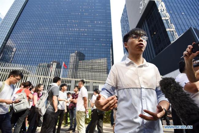 In this file photo taken on June 30, 2017, Joshua Wong Chi-fung (front) speaks during an interview in front of the Hong Kong Special Administrative Region (HKSAR) government headquarters in Hong Kong, South China. [File Photo: Xinhua]