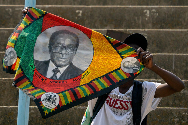 A supporter of the late former Zimbabwean president Robert Mugabe waves a piece of cloth bearing his image as mourners break into song and dance during a public send off at the Rufaro stadium in Harare on September 13, 2019. [Photo: AFP/Zinyange Auntony]