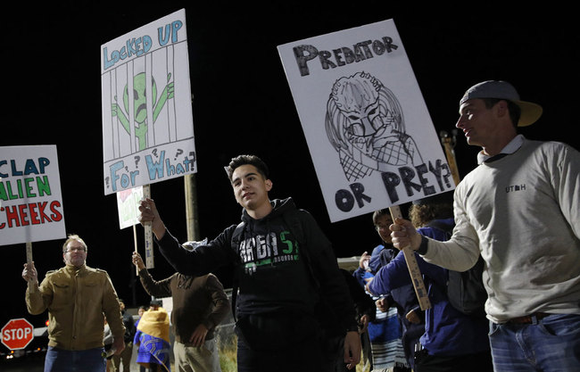 People holds signs at an entrance to the Nevada Test and Training Range near Area 51 Friday, Sept. 20, 2019, near Rachel, Nev. People gathered at the gate inspired by the "Storm Area 51" internet hoax. [Photo: AP/John Locher]