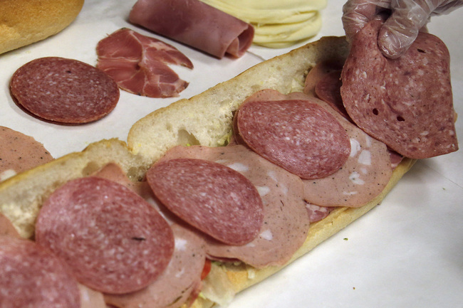 In this June 5, 2014, file photo, a man makes a submarine sandwich with mortadella, cooked salami, ham, Genoa salami and sweet capicola at a delicatessen in Massachusetts. [Photo: AP/Photo/Elise Amendola]