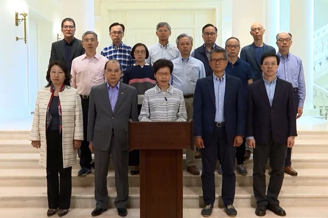 This screen grab image taken from video released on October 5, 2019 by the Government Information Service shows Hong Kong Chief Executive Carrie Lam (C) standing with her cabinet as she delivers a video message released to media organisations in Hong Kong. [Photo: AFP/ Government Information Service ] 