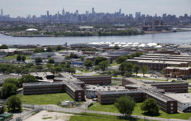 This June 20, 2014 file photo shows the Rikers Island jail complex in New York with the Manhattan skyline in the background. New York City lawmakers are considering a plan to close the notorious Rikers Island jail complex and replace it with four smaller jails. [Photo: AP]