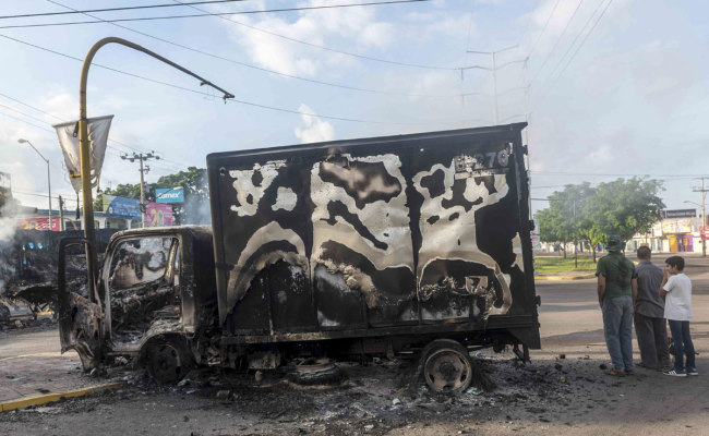 A burnt out truck used by gunmen smolders on an intersection, a day after street battles between gunmen and security forces in Culiacan, Mexico, Friday Oct. 18, 2019. [Photo: AP]