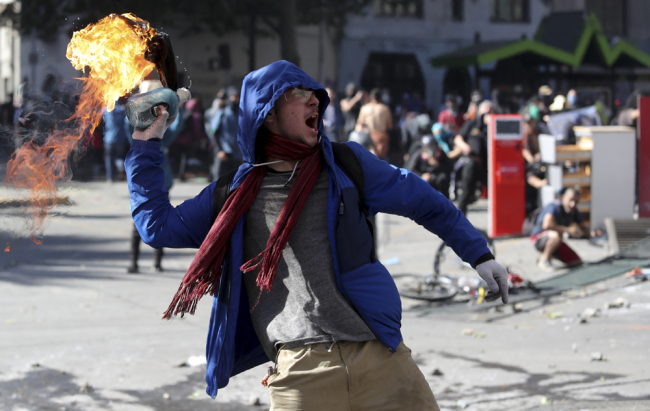 A protester throws a firebomb amid a march by students and union members in Santiago, Chile, Monday, Oct. 21, 2019. [Photo: AP/Miguel Arenas]
